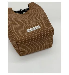 Detailaufnahme des verstärkten Bodens und braunen Karostoffs dieser Beuteltasche