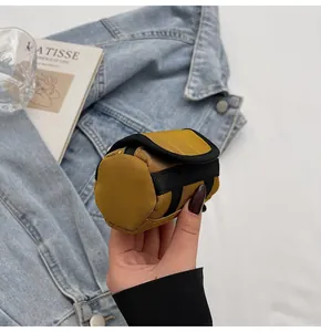 Detailed view of ginger yellow mini cylindrical canvas pouch held by hand for accessories