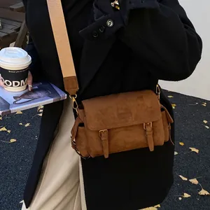 Brown frosted messenger bag with vintage buckles and wide strap in an urban street setting