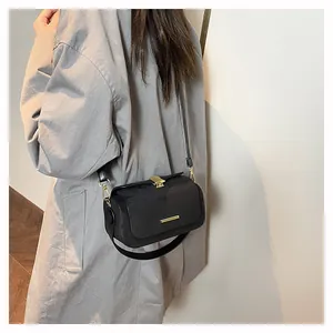 Dettaglio della borsa a tracolla nera elegante con fibbia dorata sulla spalla del modello