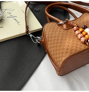 Detail of a brown woven textured handbag with retro colorful wooden bead charm and long strap