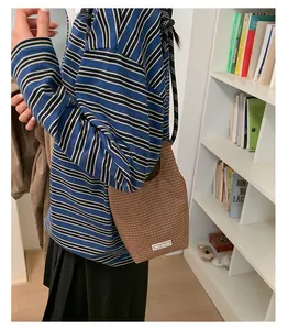 Detailaufnahme der braun karierten Handtasche mit Logo-Etikett in lässiger Umgebung