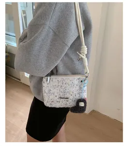 Gros plan du sac bandoulière en peluche blanche à pois colorés avec breloque cœur