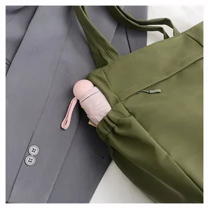 Dettaglio della borsa tote verde oliva con tasca laterale elastica e ombrello rosa
