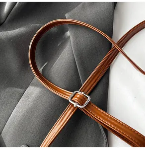 Close-up of caramel brown leather shoulder strap with silver buckle and fine stitching