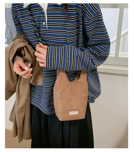 Detail einer kompakten braun karierten Handtasche mit Chic Graze Label im Lifestyle-Look
