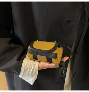 Close-up of mini yellow canvas storage bag with a black snap hook and zip closure