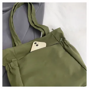 Dettaglio della borsa tote verde oliva con coulisse laterali e tasca frontale con zip interna