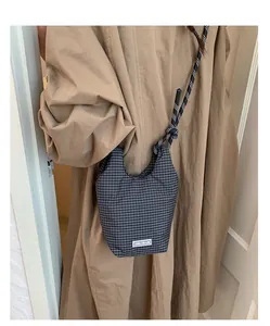 Detail der karierten Canvas-Beuteltasche mit Chic-Craze-Label und geflochtenem Gurt