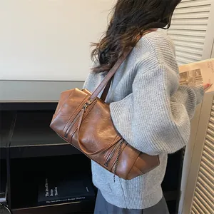 Sac sous le bras vintage marron avec fermetures éclair et détails de chaîne sur un mannequin