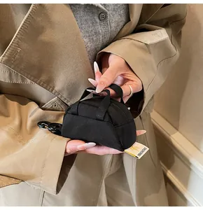 Detailed macro view of a mini black canvas bag with top handles and a metal carabiner