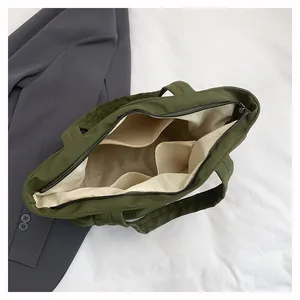 Interno della borsa tote verde oliva con fodera bianca, zip principale e due tasche