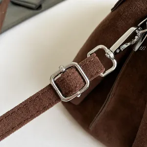 Dettaglio della tracolla regolabile in pelle scamosciata con fibbia argento su borsa marrone