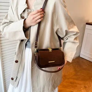 Borsa a tracolla in pelle scamosciata marrone con dettagli dorati e trench beige