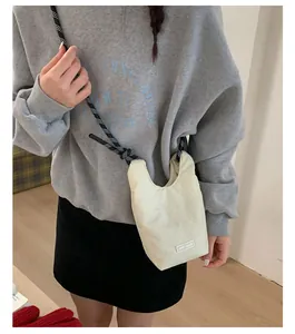Detail der beige Umhängetasche mit schwarz-weiß gewebtem Seilschultergurt und Chic-Logo