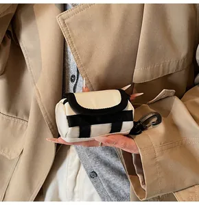 Close-up of mini canvas earphone pouch with black trim and lobster clasp on trench coat
