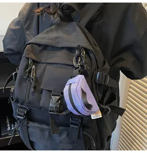 Close-up of functional black nylon backpack with a decorative purple mini coin pouch charm
