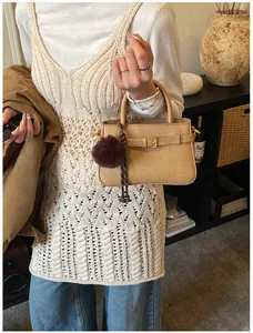 Detail of khaki woven bucket bag with leather strap and plush pompom on model