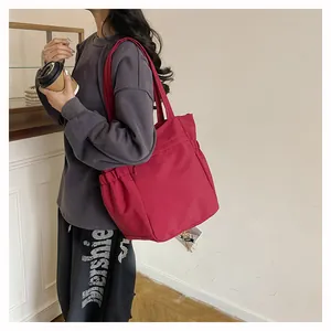 Dettaglio della borsa tote rossa con tasche laterali a coulisse e grande capacità interna