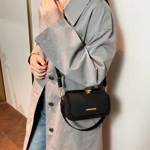 Borsa a tracolla nera opaca con fibbia dorata su modella in trench grigio e jeans blu