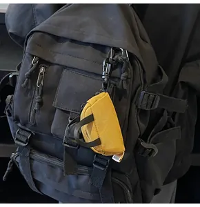 Close-up of yellow canvas mini bag charm with zipper hanging on a black backpack