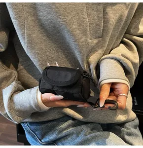 Close-up of a black tactical mini canvas pouch with a carabiner clip in hand