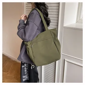 Grande borsa tote in nylon verde militare con tasche laterali sulla spalla della modella
