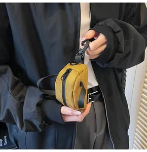 Detail view of mustard yellow mini canvas pouch with black zipper and clip attachment