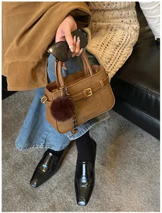 Detail of brown vintage bucket bag with stripe texture and plush charm pendant