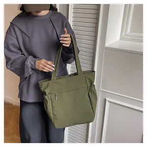 Dettaglio borsa tote verde oliva con tasca frontale zip e scomparti laterali elastici