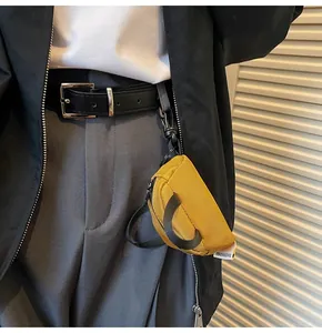 Mini mustard yellow nylon coin purse hanging on clothing with black hook and woven label