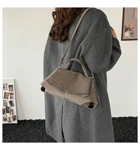 Dettaglio della borsa in pelle opaca marrone scuro in un ambiente minimalista