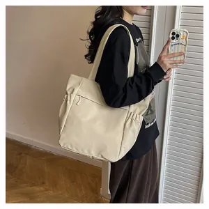 Dettaglio della borsa tote oversize bianco crema con coulisse laterale e tasca zip frontale