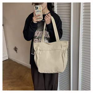 Dettaglio della borsa tote crema con tasche laterali e tasca frontale con zip
