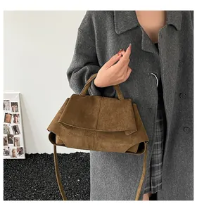 Dettaglio della borsa a mano trapezoidale in pelle scamosciata marrone con tracolla sottile