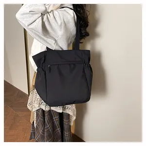 Vista laterale della borsa tote grande in nylon nero con tasche laterali e tessuto liscio