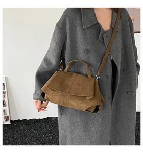 Dettaglio della borsa in pelle scamosciata marrone scuro indossata con un cappotto di lana grigio