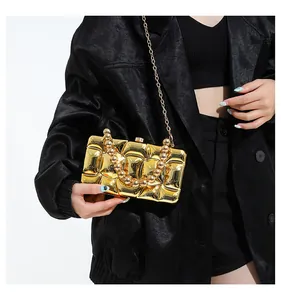 Close-up of golden geometric evening clutch with beaded handle and chain strap