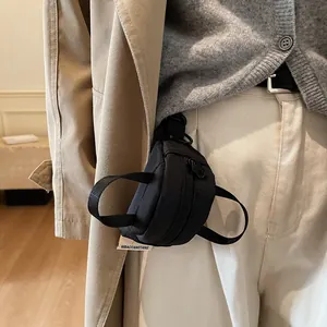 Mini black canvas pendant bag for lipstick and earphones attached to beige trench coat