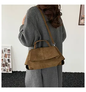 Borsa a tracolla scamosciata marrone indossata con un lungo cappotto grigio di lana