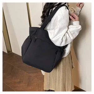 Vista laterale di una grande borsa tote nera con tasche e cerniera su modella