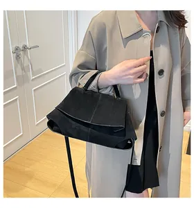 Dettaglio borsa a mano nera in pelle opaca con patta pieghevole e texture satinata