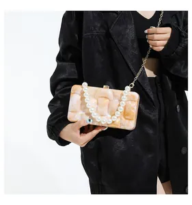 Detail of marble pattern acrylic handbag with faux pearl handle and gold chain