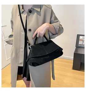 Dettaglio di borsa a mano in pelle scamosciata nera opaca con trench per un look invernale