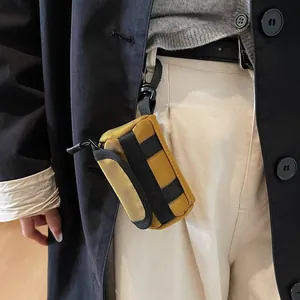 Mustard yellow canvas mini cylinder bag for lipstick and earphones clipped on pants