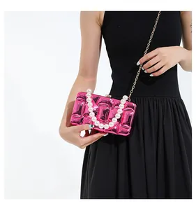 Detailed view of rose red quilted metallic acrylic bag with pearl handle and gold chain