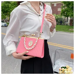 Détail du sac à main rose rayé avec poignée en perles et fermoir en métal vintage