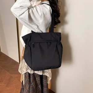 Grande borsa tote in nylon nero con tasche laterali e zip indossata dal modello