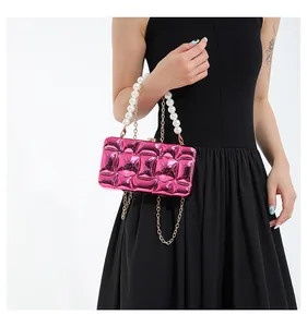 Detail of rose red metallic lattice clutch bag with pearl handle and metal chain
