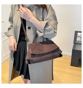 Dettaglio borsa a mano in pelle scamosciata marrone scuro con texture morbida e patta